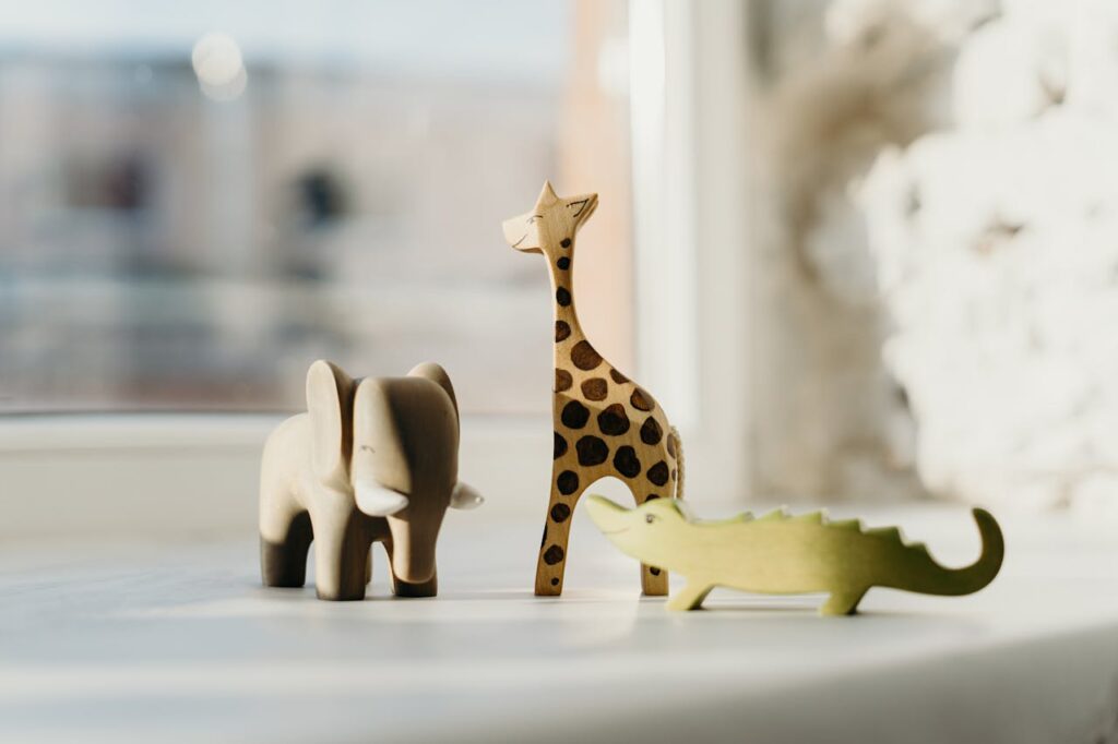 Mastering the First Impression: Your intriguing post title goes here Set of wooden animal toys including giraffe, elephant, and crocodile on a sunny windowsill.