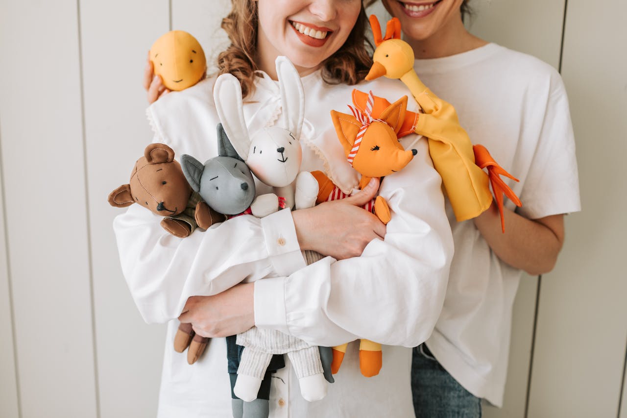 Crafting Captivating Headlines: Your awesome post title goes here Two women smiling and holding a variety of colorful plush and hand puppets indoors.